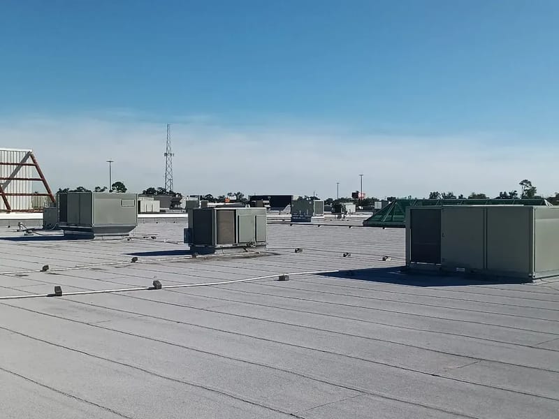 Commercial rooftop HVAC units on a flat roof under a blue sky