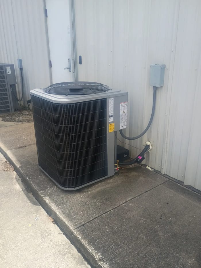 A new outdoor AC unit beside a metal building with a new disconnect box